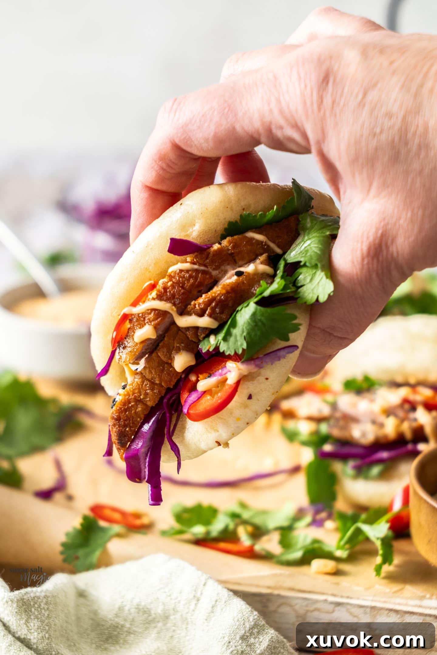 A hand holding a duck bao bun.
