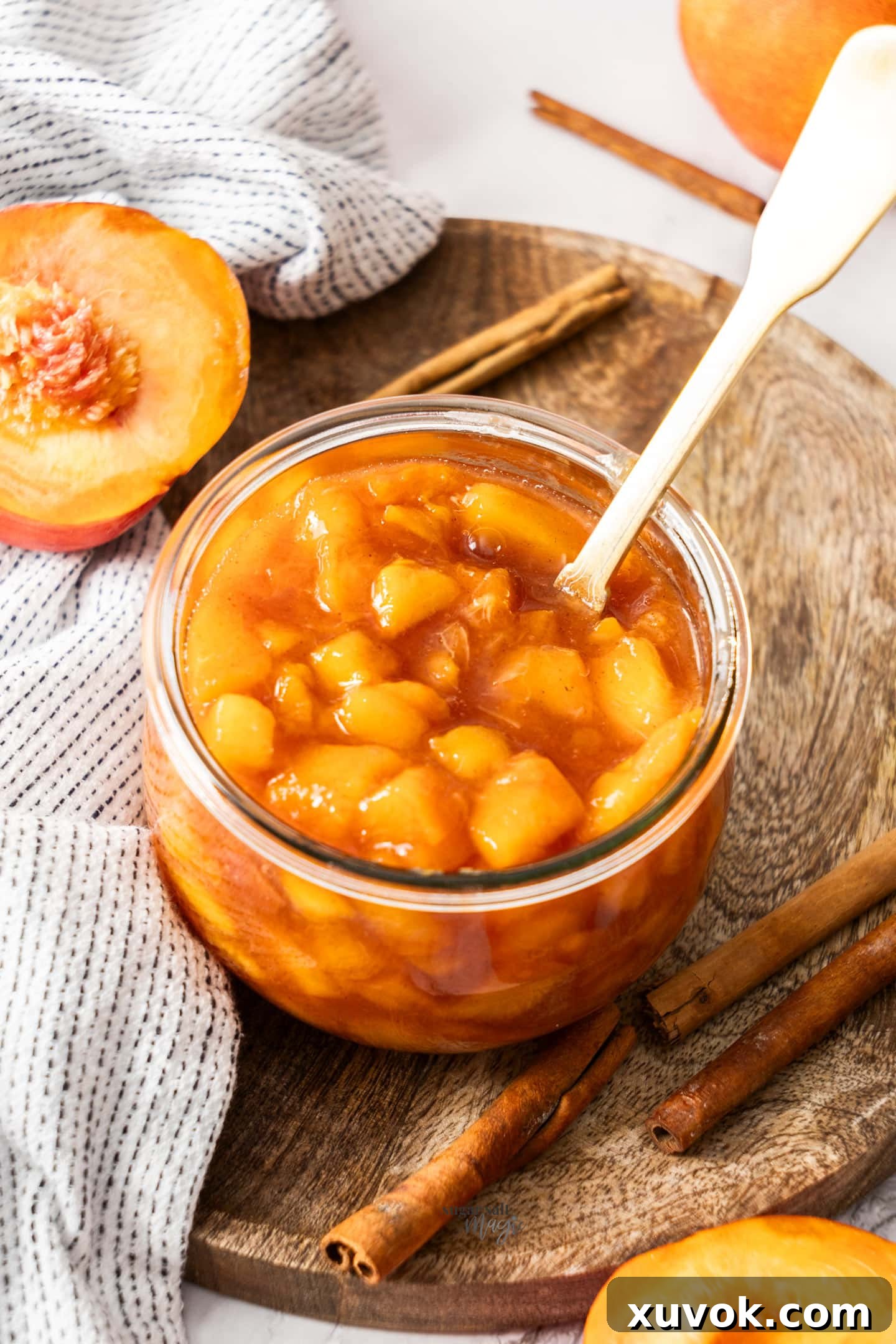 A jar of homemade peach compote sitting on a rustic wooden board, ready to be enjoyed.