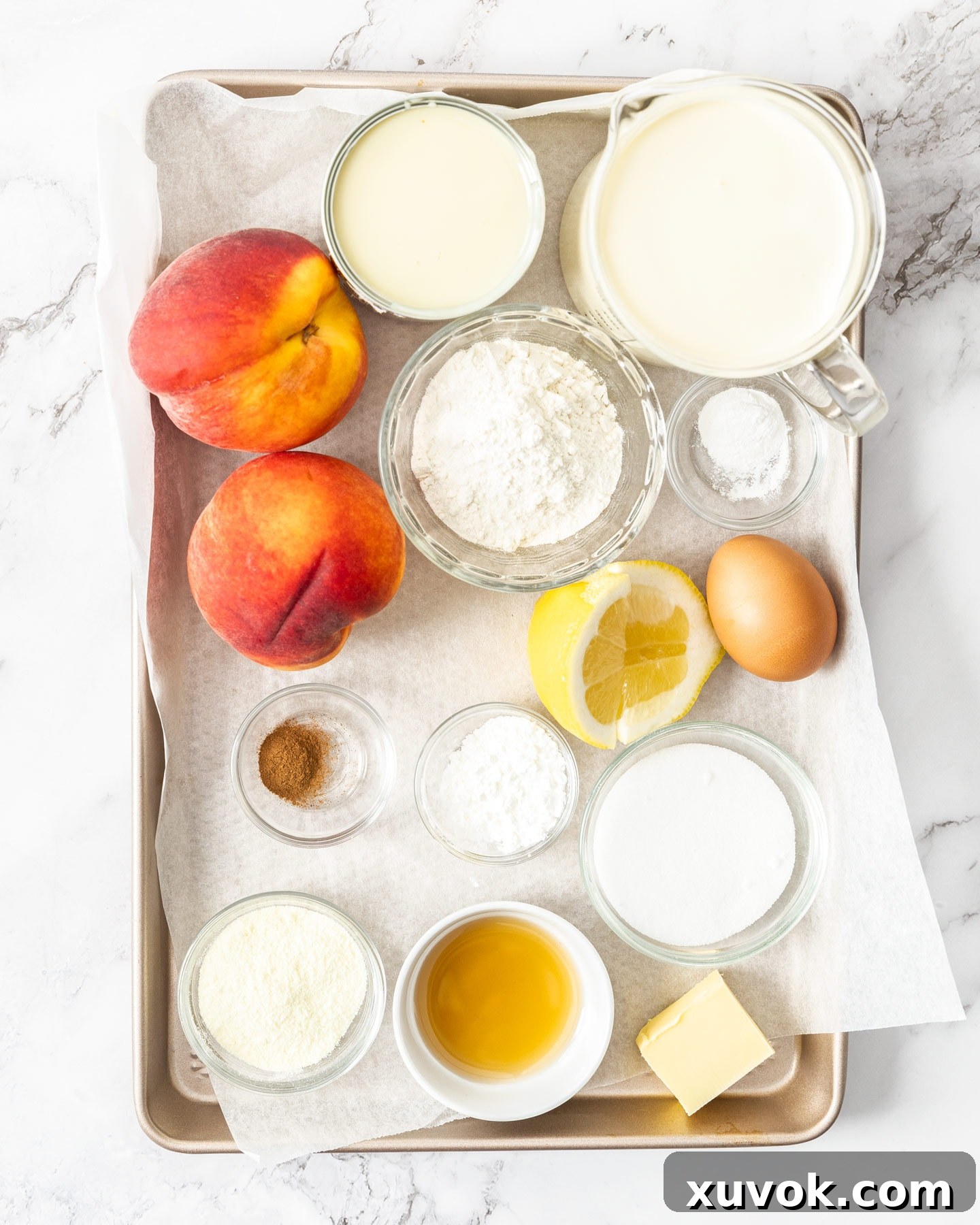 Ingredients for homemade peach cobbler ice cream laid out on a baking tray, showing fresh peaches, flour, and cream.