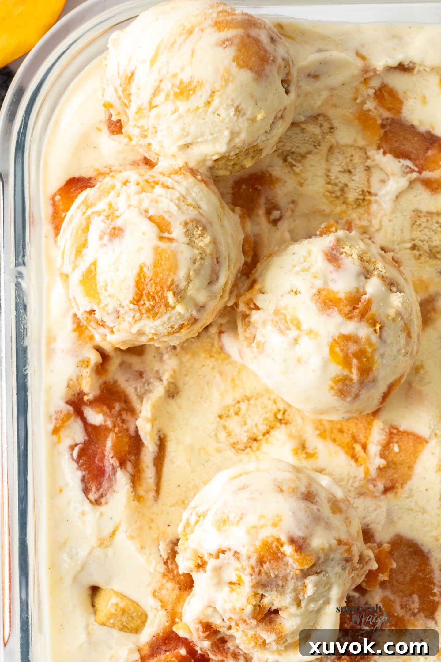 Four generous scoops of peach cobbler ice cream arranged on top of the tub, ready to serve.