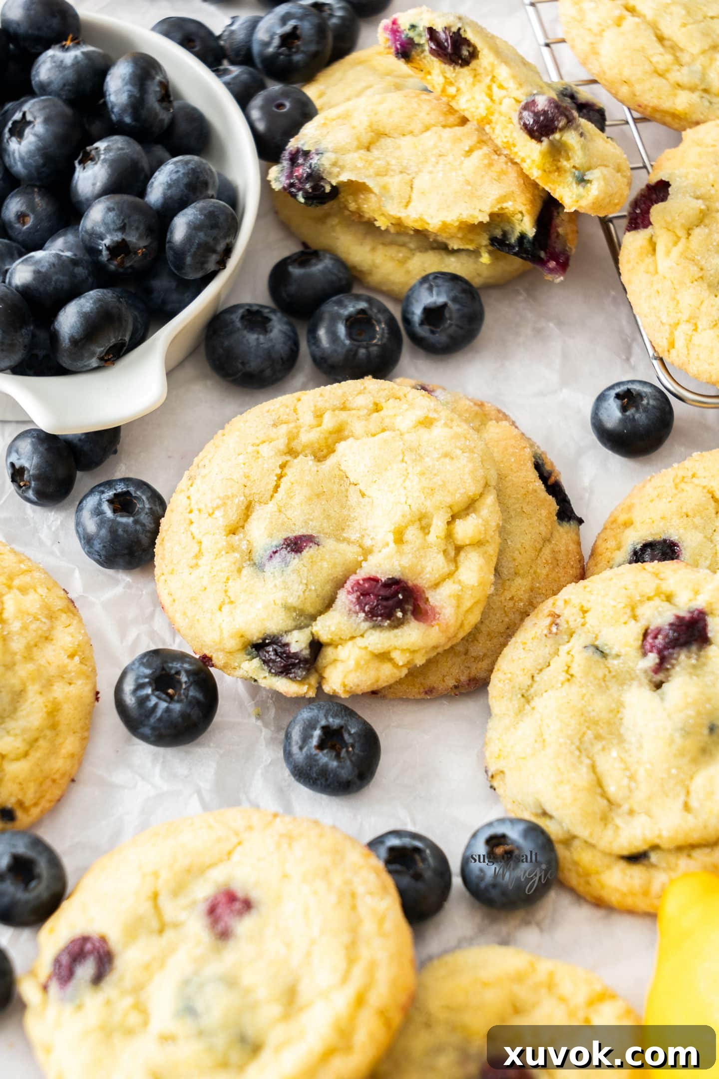 A couple of stacked lemon blueberry cookies surrounded by fresh blueberries.