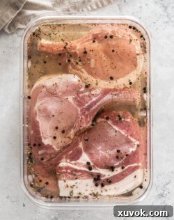 Pork chops in brine in a glass dish.