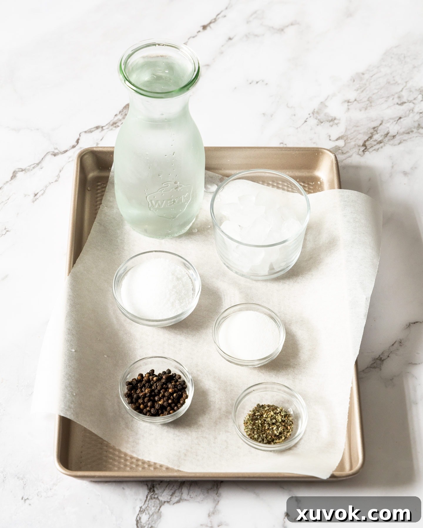 A visual display of the simple yet essential ingredients for a basic pork brine: water, cooking salt, sugar, black peppercorns, and dried sage.