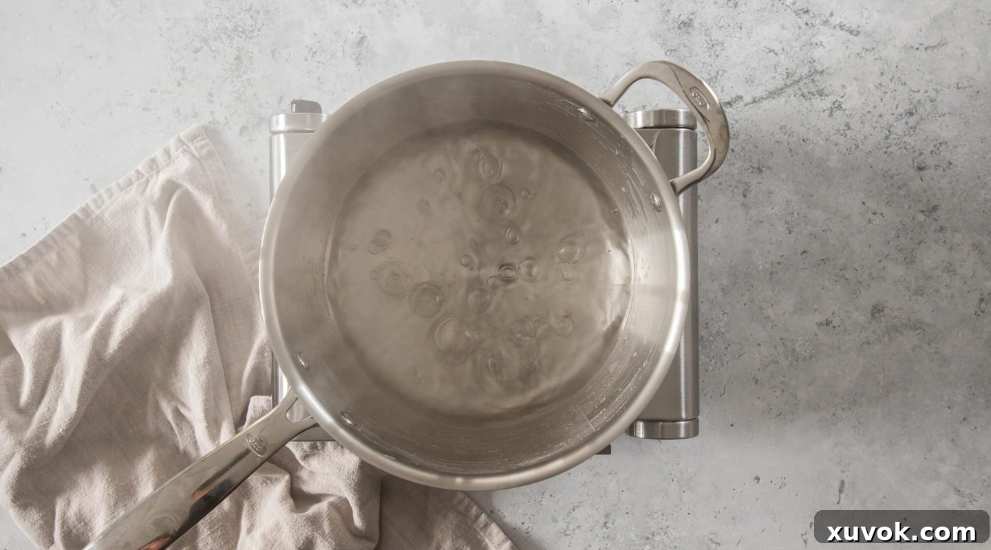 Water boiling vigorously in a saucepan on a stove, indicating the brine base has reached temperature.