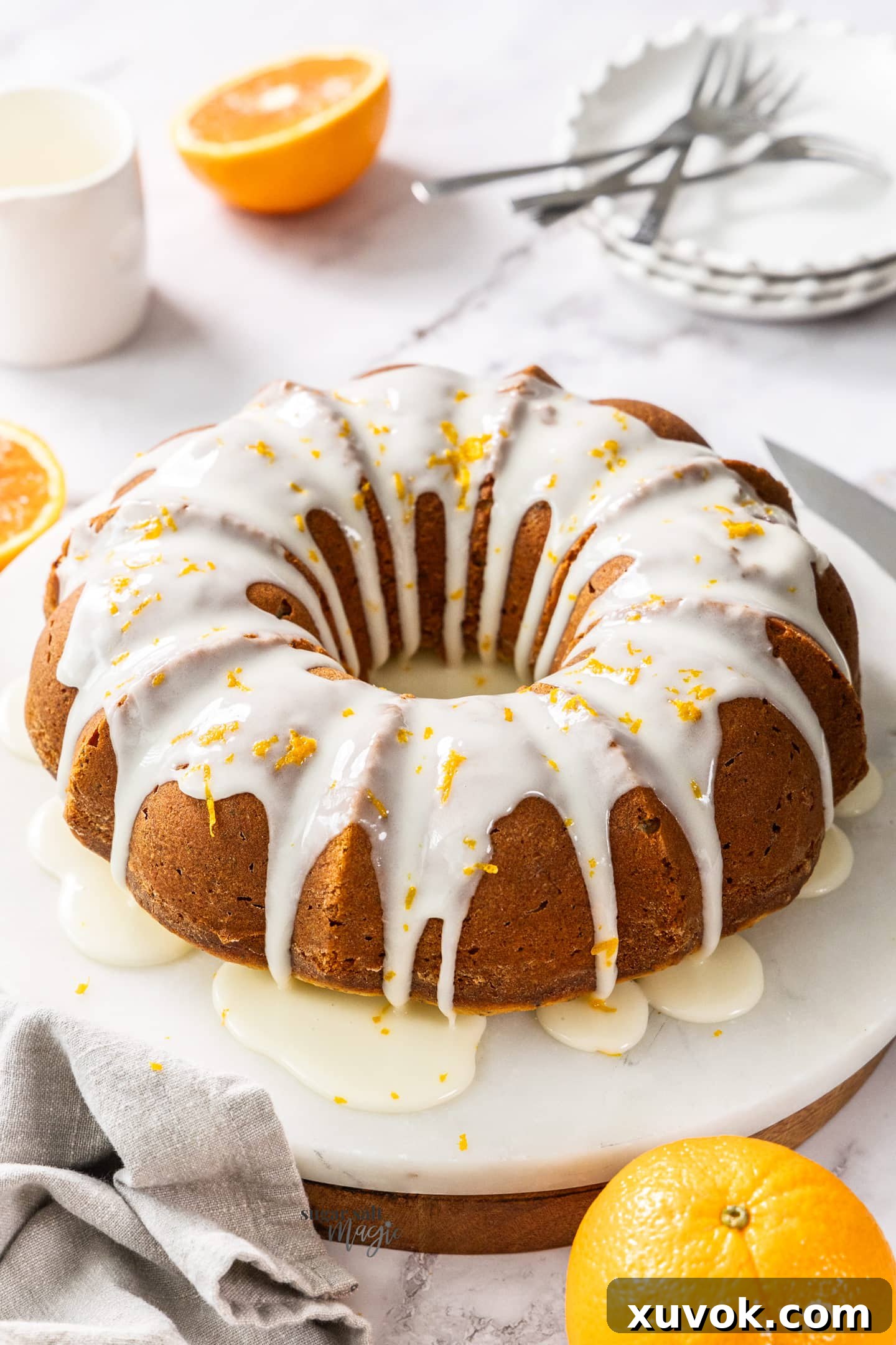 A beautifully glazed orange and poppy seed bundt cake on a marble platter, ready to be served, highlighting its intricate design and vibrant color.