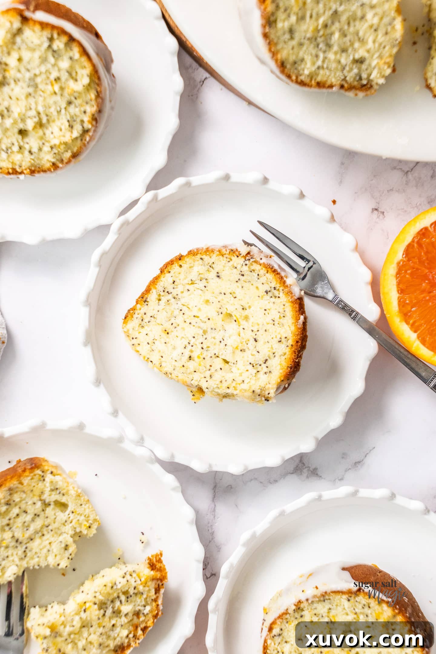 A perfectly portioned slice of orange bundt cake on a white dessert plate, showing the fluffy texture and poppy seed distribution.