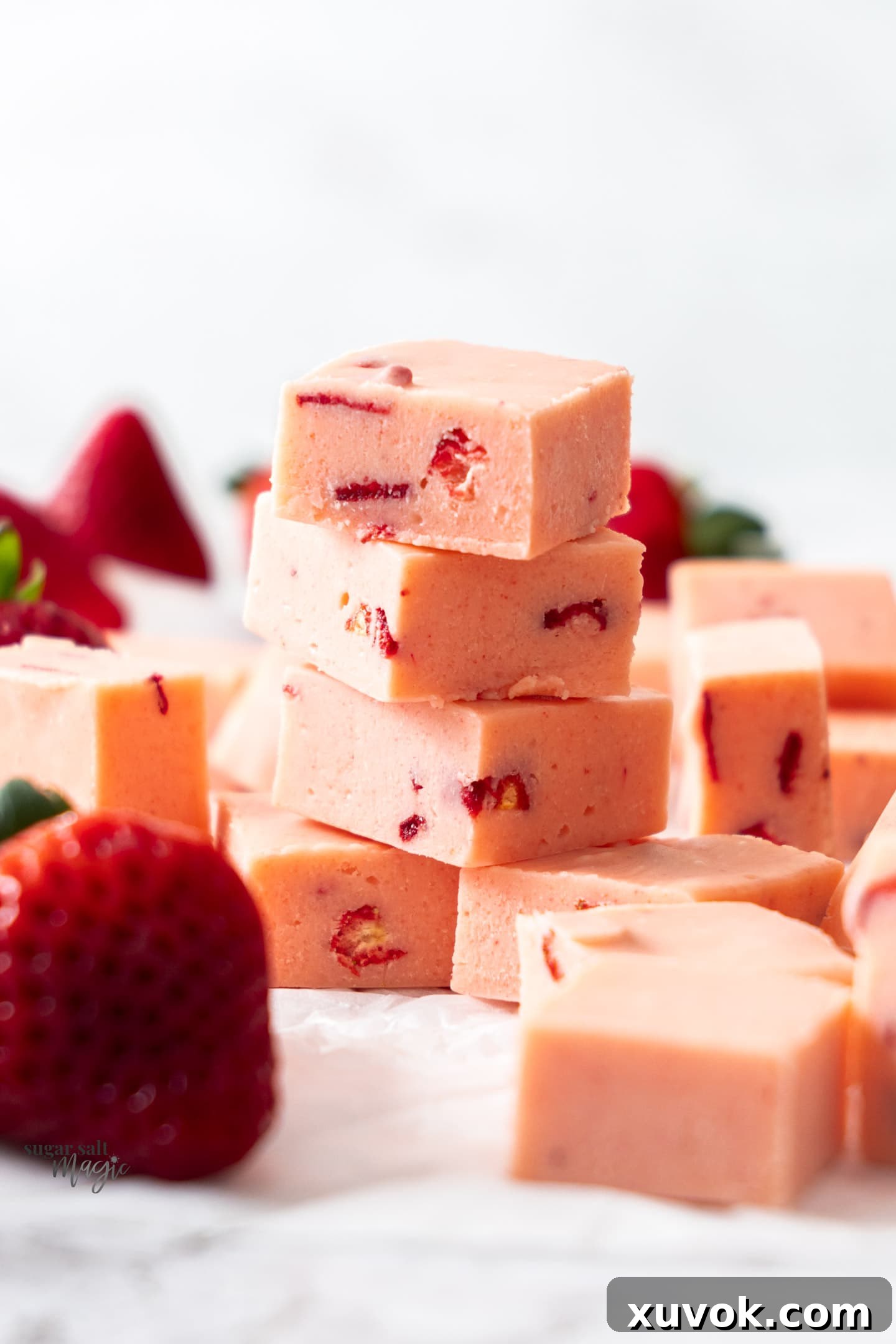 A stack of 4 pieces of strawberry fudge, showcasing its vibrant pink color and smooth texture.