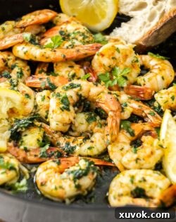 A pile of cooked sizzling garlic prawns served in a cast iron skillet, garnished with fresh parsley.