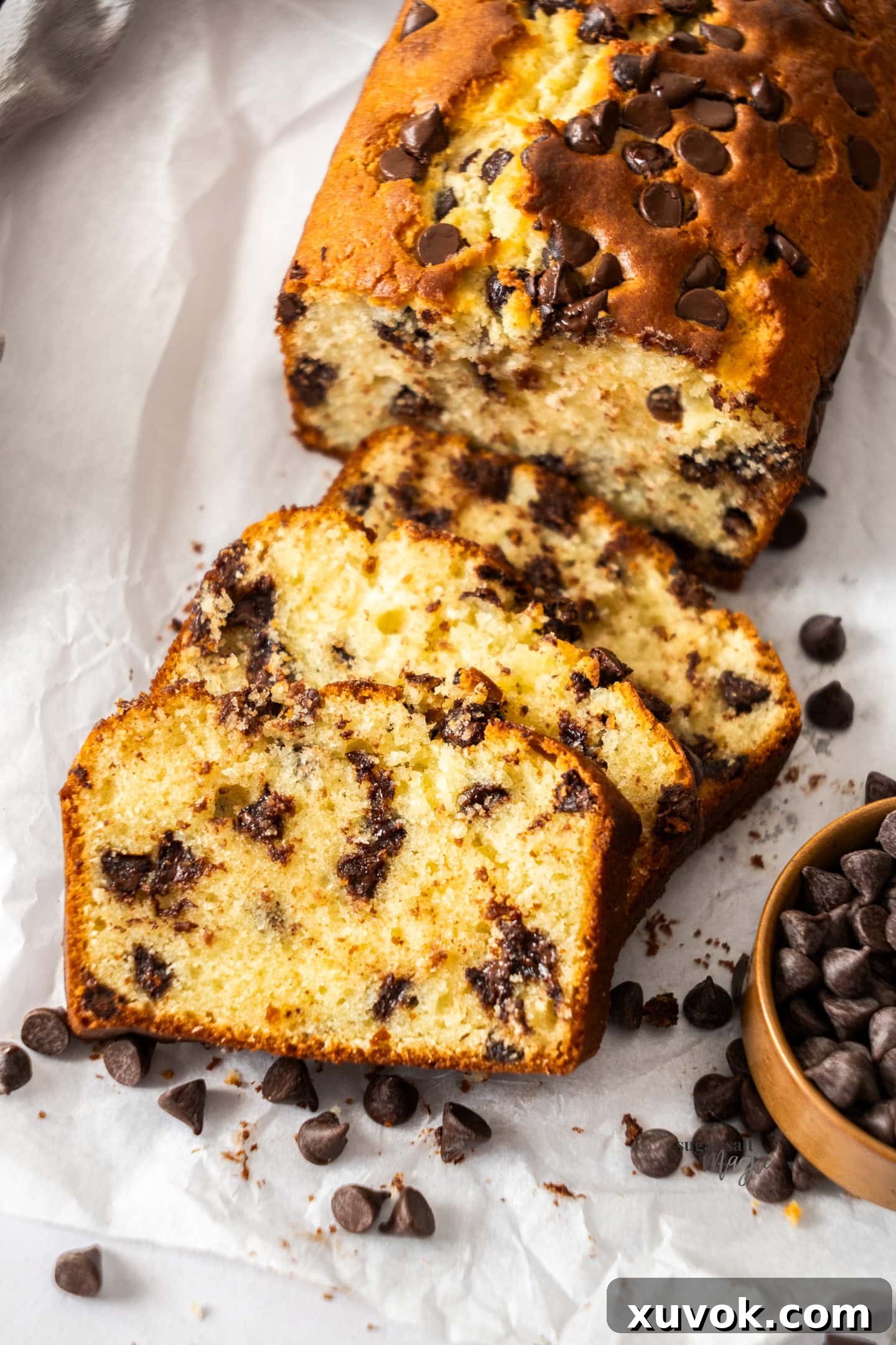 A close-up view of several thick slices of chocolate chip loaf cake, revealing the moist crumb and abundant, perfectly melted chocolate chips within each slice.