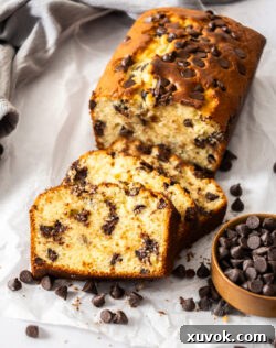 Several slices of chocolate chip loaf cake leaning against each other on a white surface, showing off their golden crust and chocolatey interior.