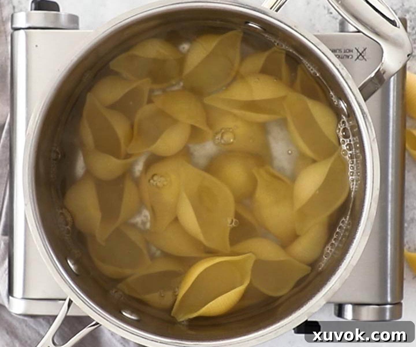Giant pasta shells in a saucepan of water.