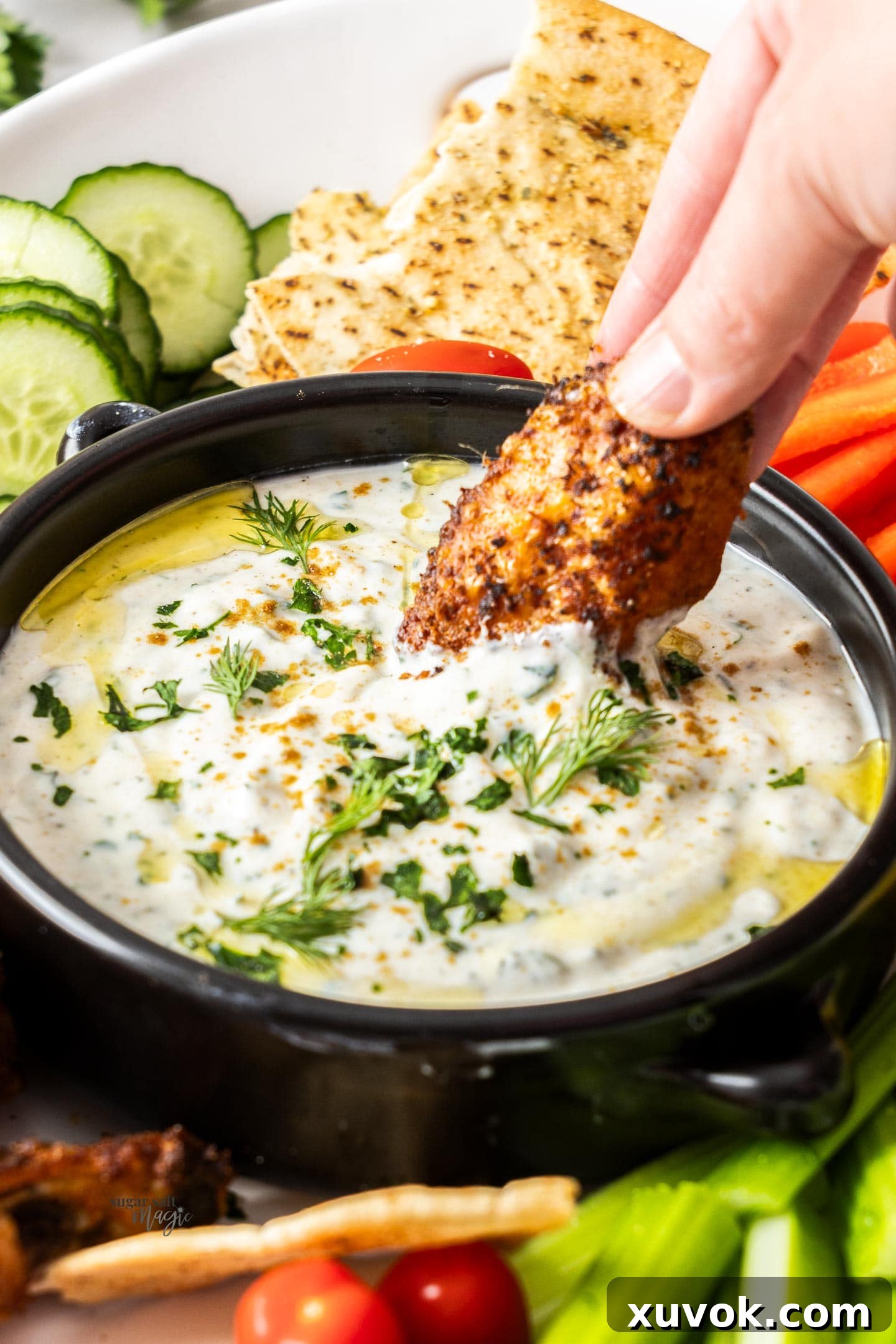 A chicken wing being dipped into yoghurt dip.
