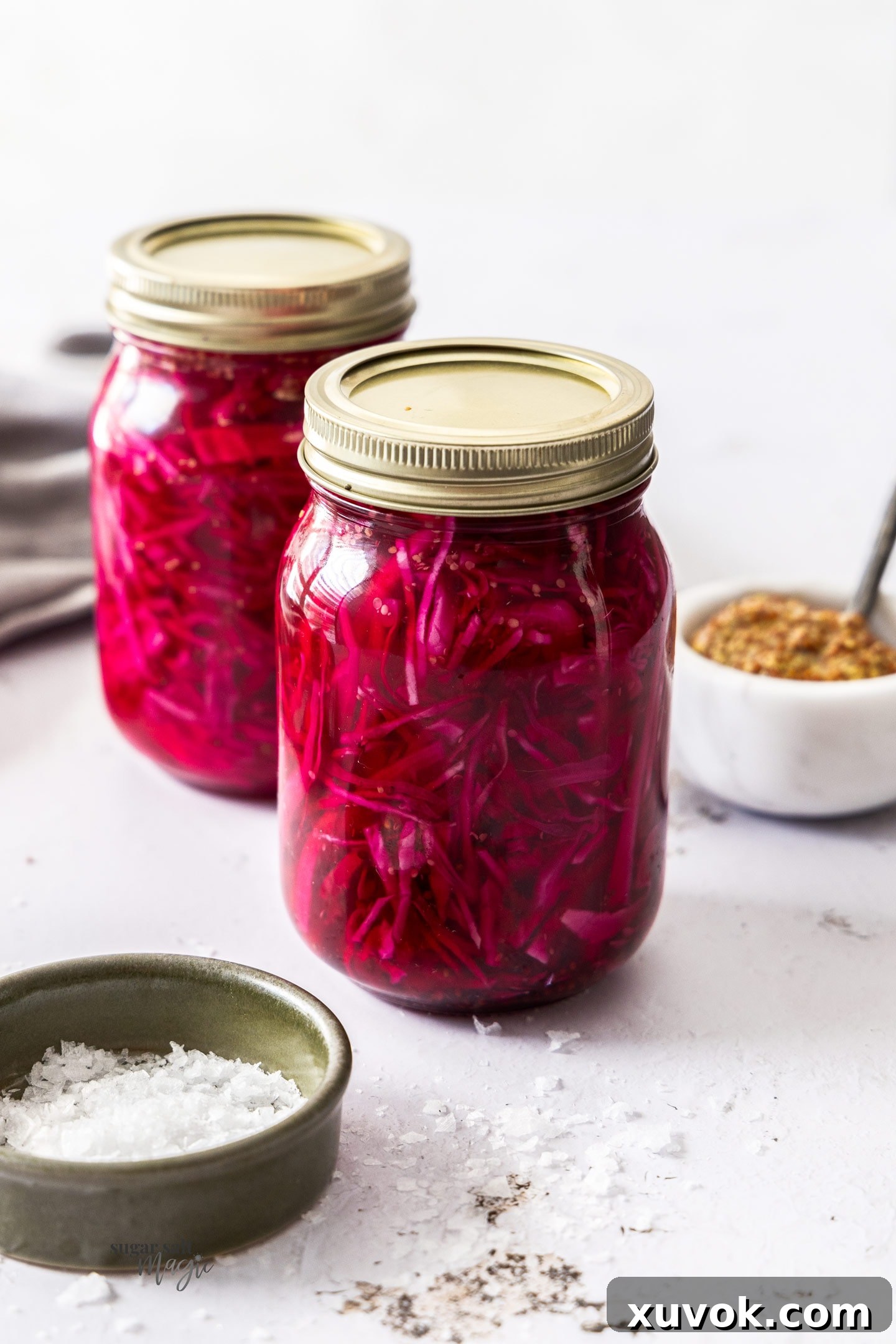Two mason jars filled with vibrant pickled red cabbage, showcasing its appealing color and texture.