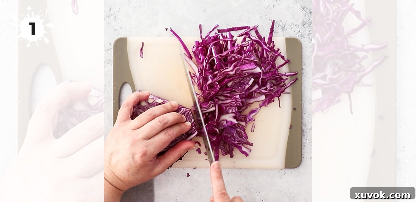 A person finely slicing red cabbage on a wooden chopping board.