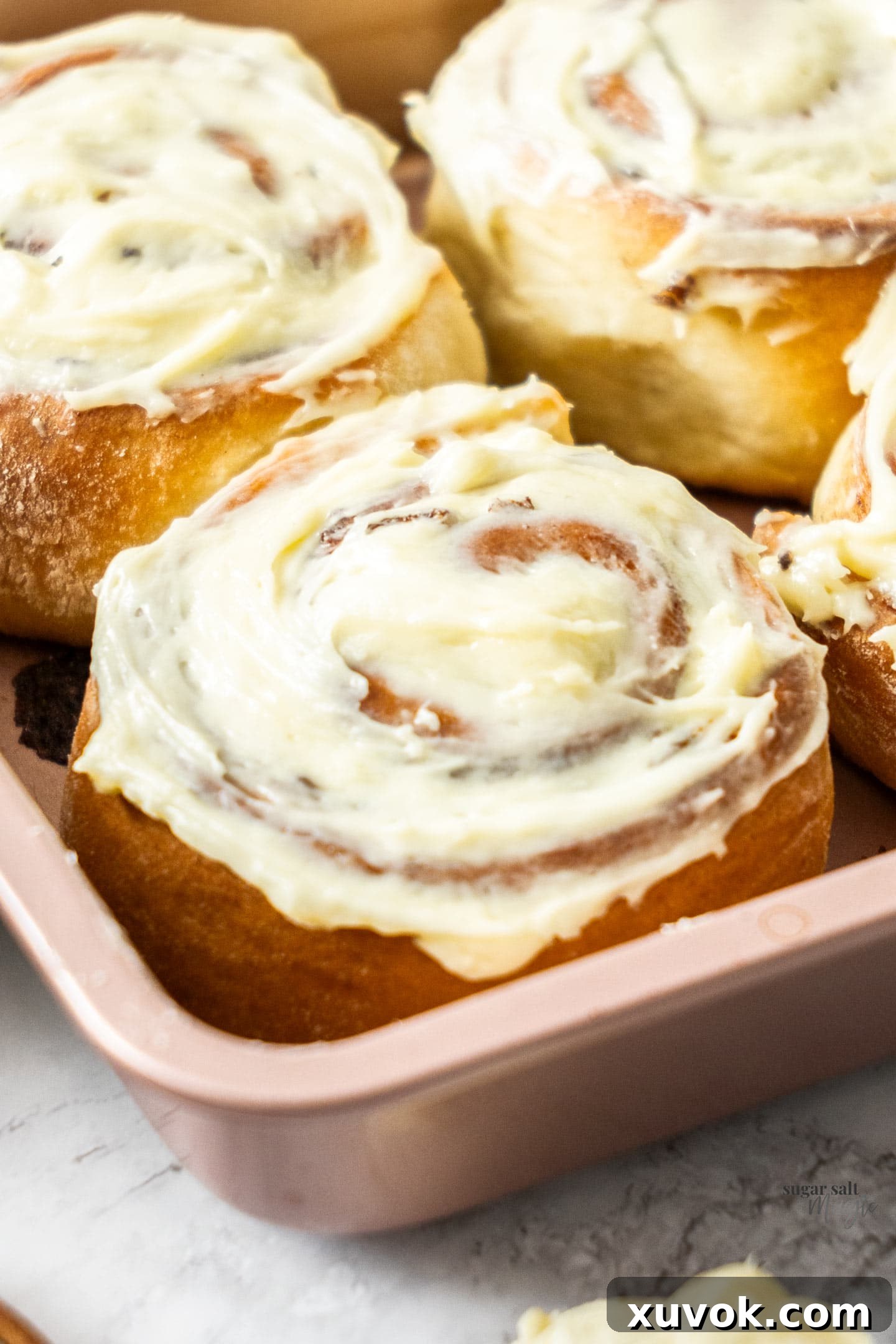 Closeup of a cinnamon roll, showcasing its gooey texture and generous cream cheese frosting.