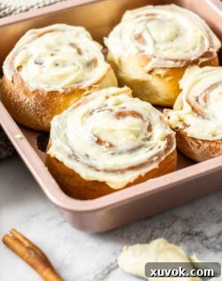 4 cinnamon rolls in a square baking pan.