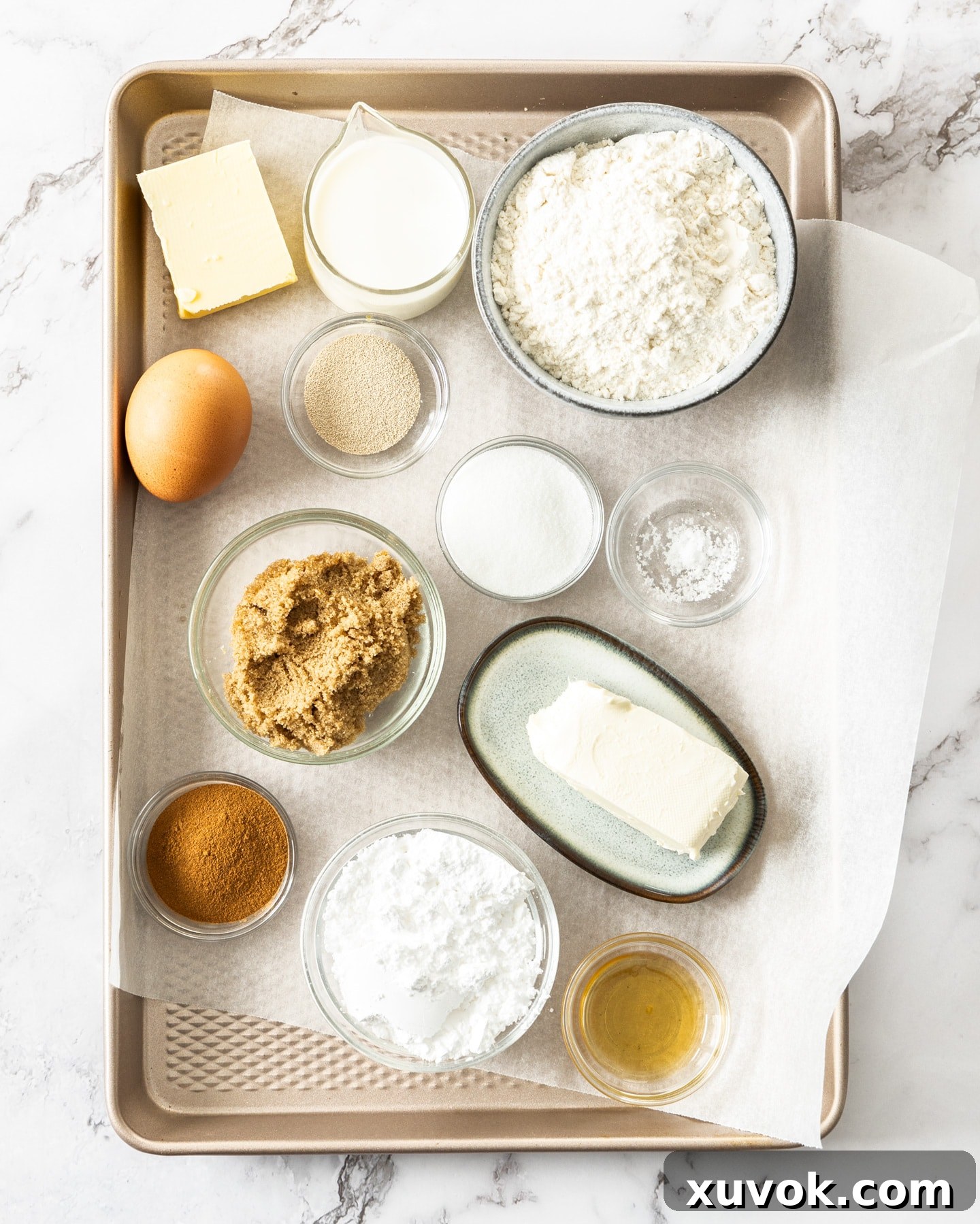 Various ingredients laid out for making cinnamon rolls, including milk, flour, sugar, butter, and cinnamon.