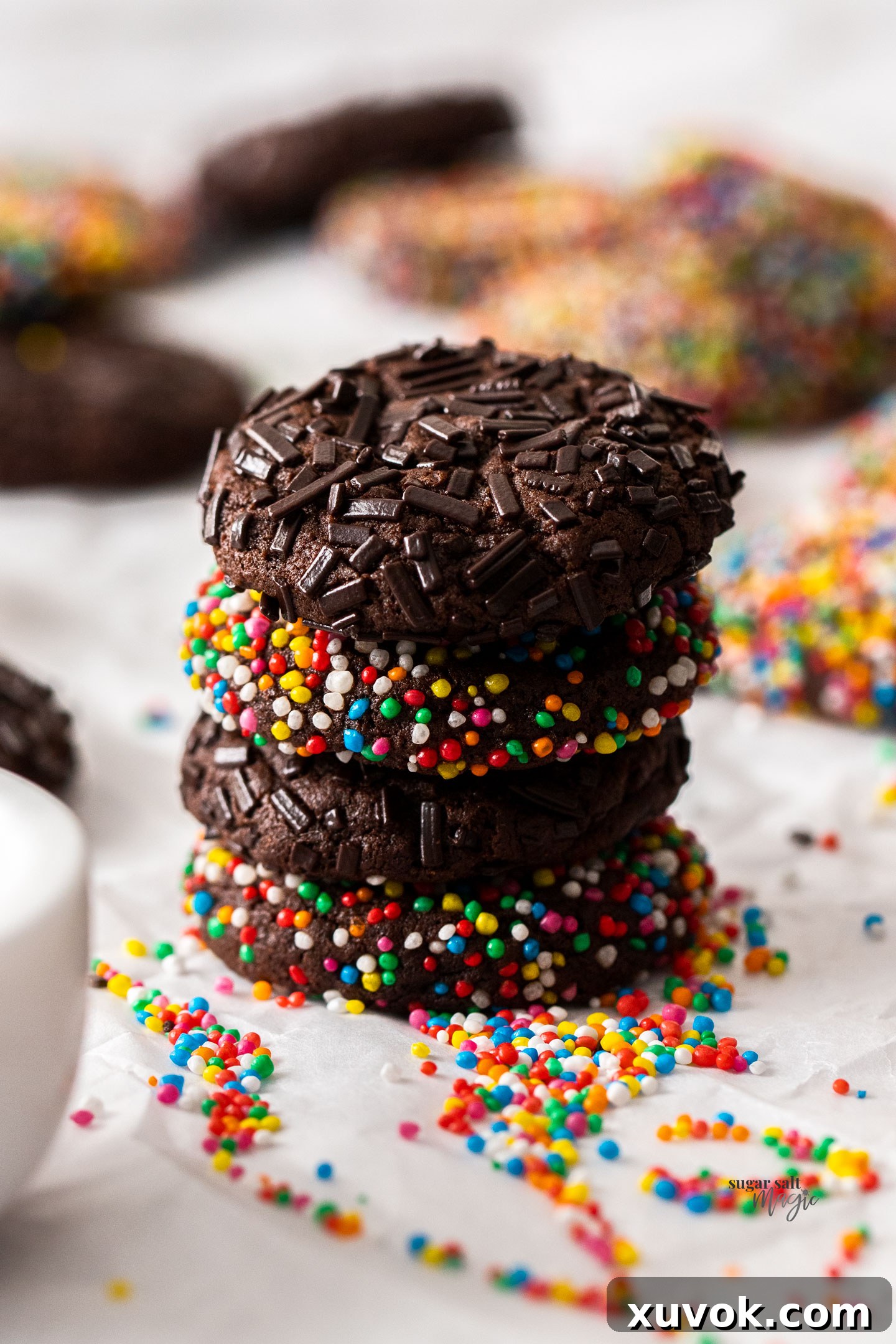 A beautifully stacked tower of four chocolate sprinkle cookies, showcasing their thick, soft texture and colorful sprinkles.