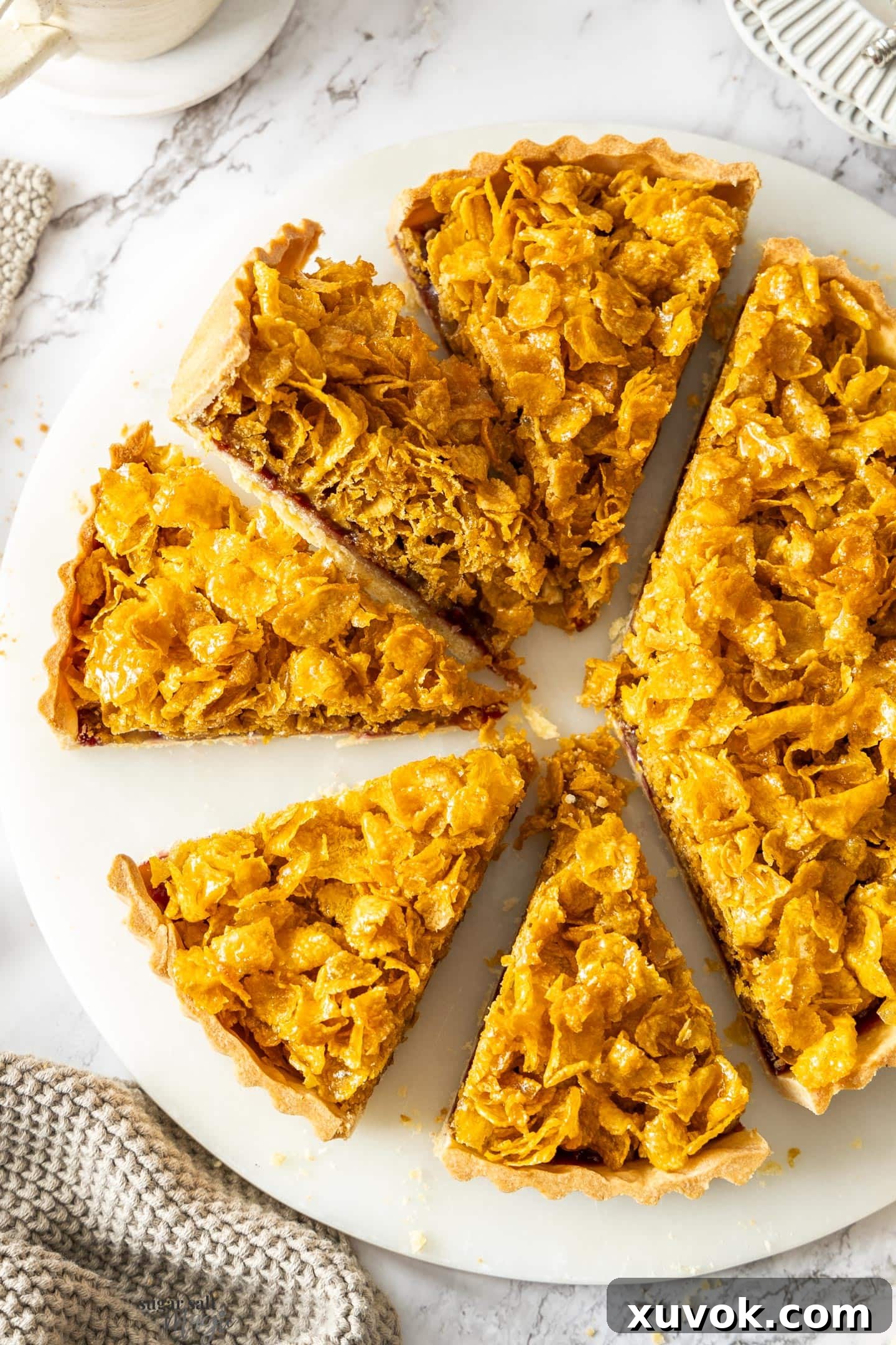 A beautifully baked Cornflake Tart, cut into perfect slices, showcasing its golden, crunchy topping and rich jam layer. A truly nostalgic British dessert.