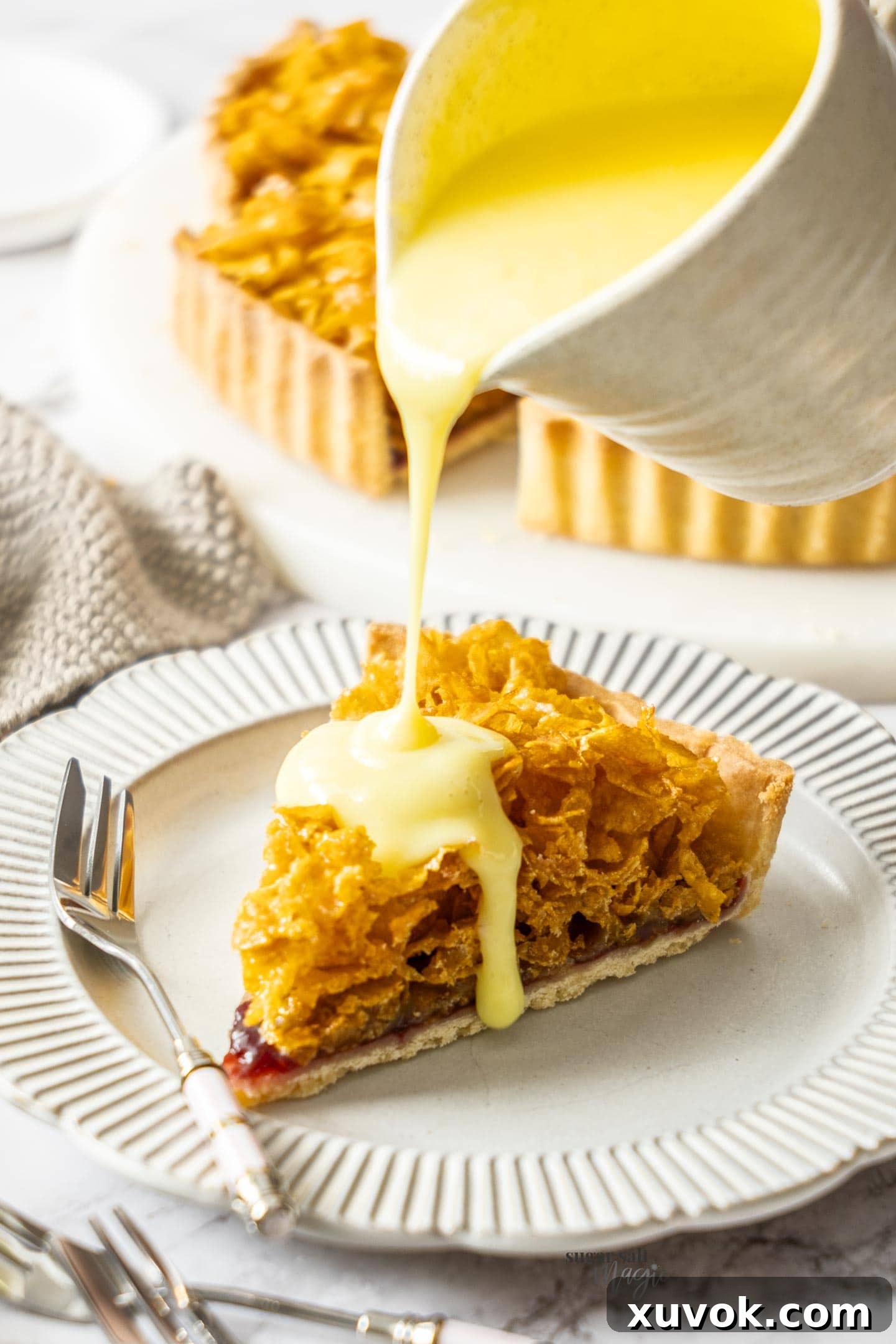A luscious slice of Cornflake Tart being drizzled with warm, creamy custard, enhancing its classic British dessert appeal.