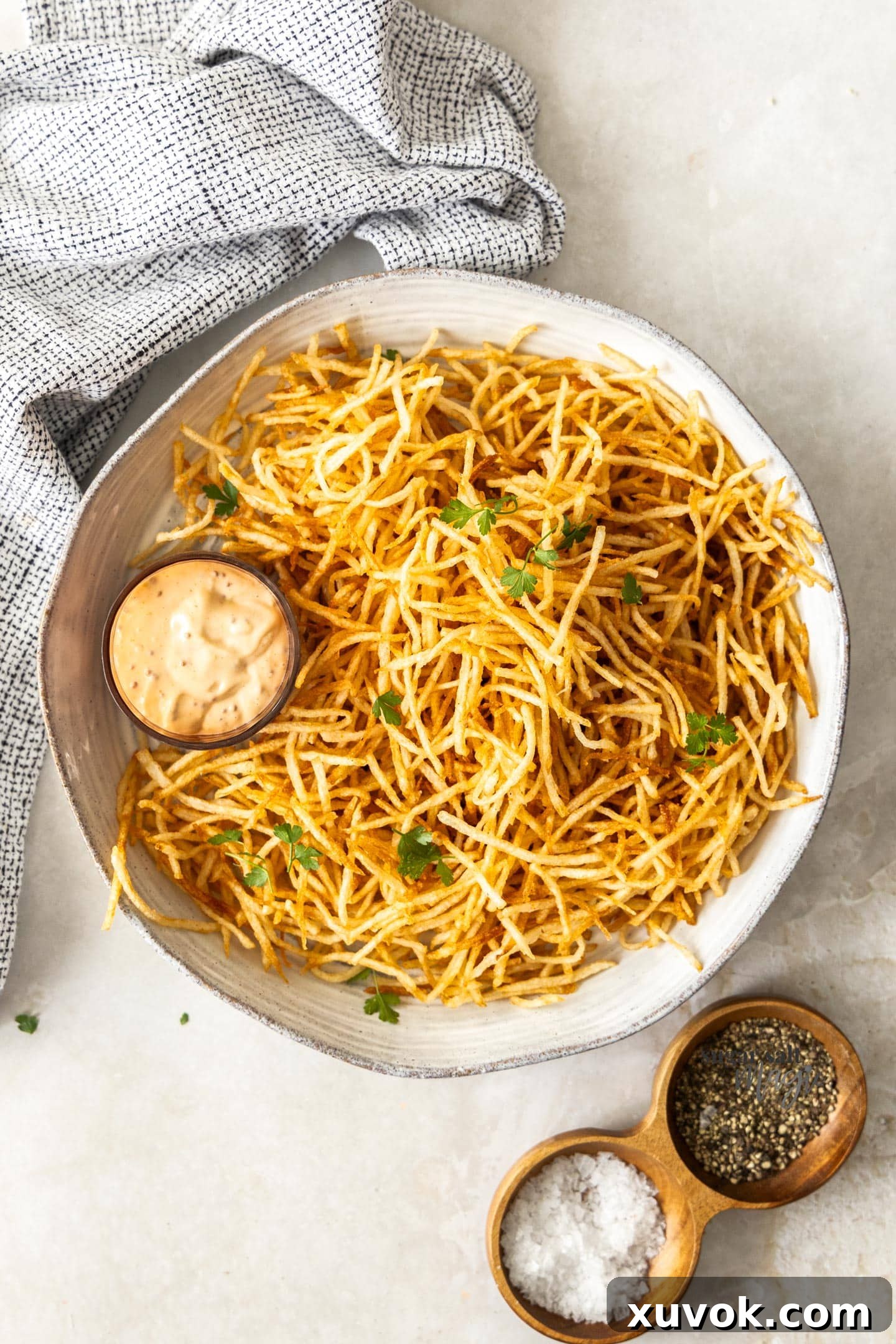 A top-down view of a generously filled bowl of perfectly golden and crispy shoestring fries, lightly seasoned and ready to be enjoyed. The thin, delicate strands create an inviting texture, promising a satisfying crunch with every bite.