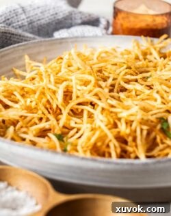 Closeup of perfectly golden and crispy shoestring fries in a bowl, showing their slender, inviting texture.