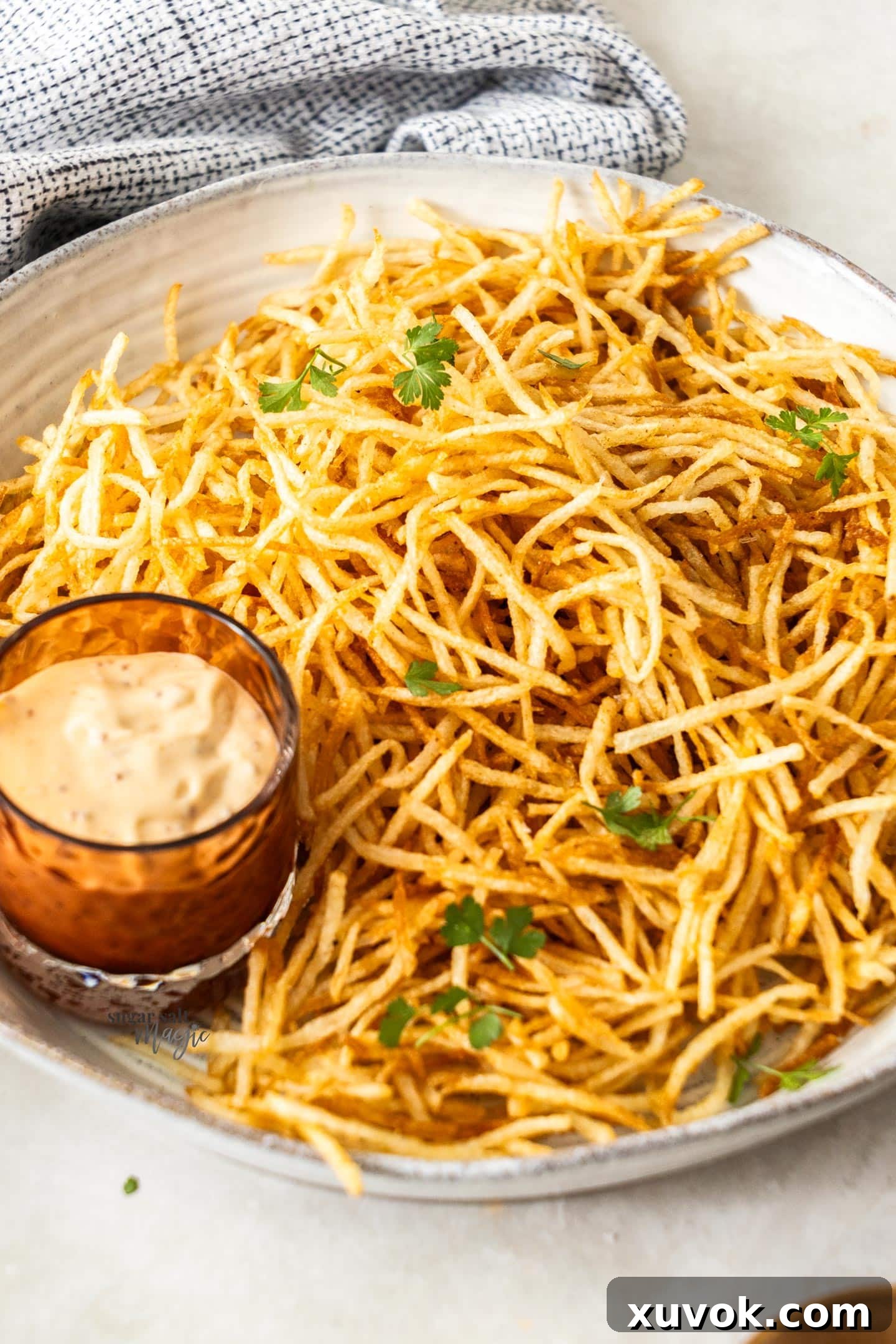 A bowl of golden, crispy shoestring fries, perfectly seasoned, resting on a rustic wooden surface, inviting you to grab a handful.