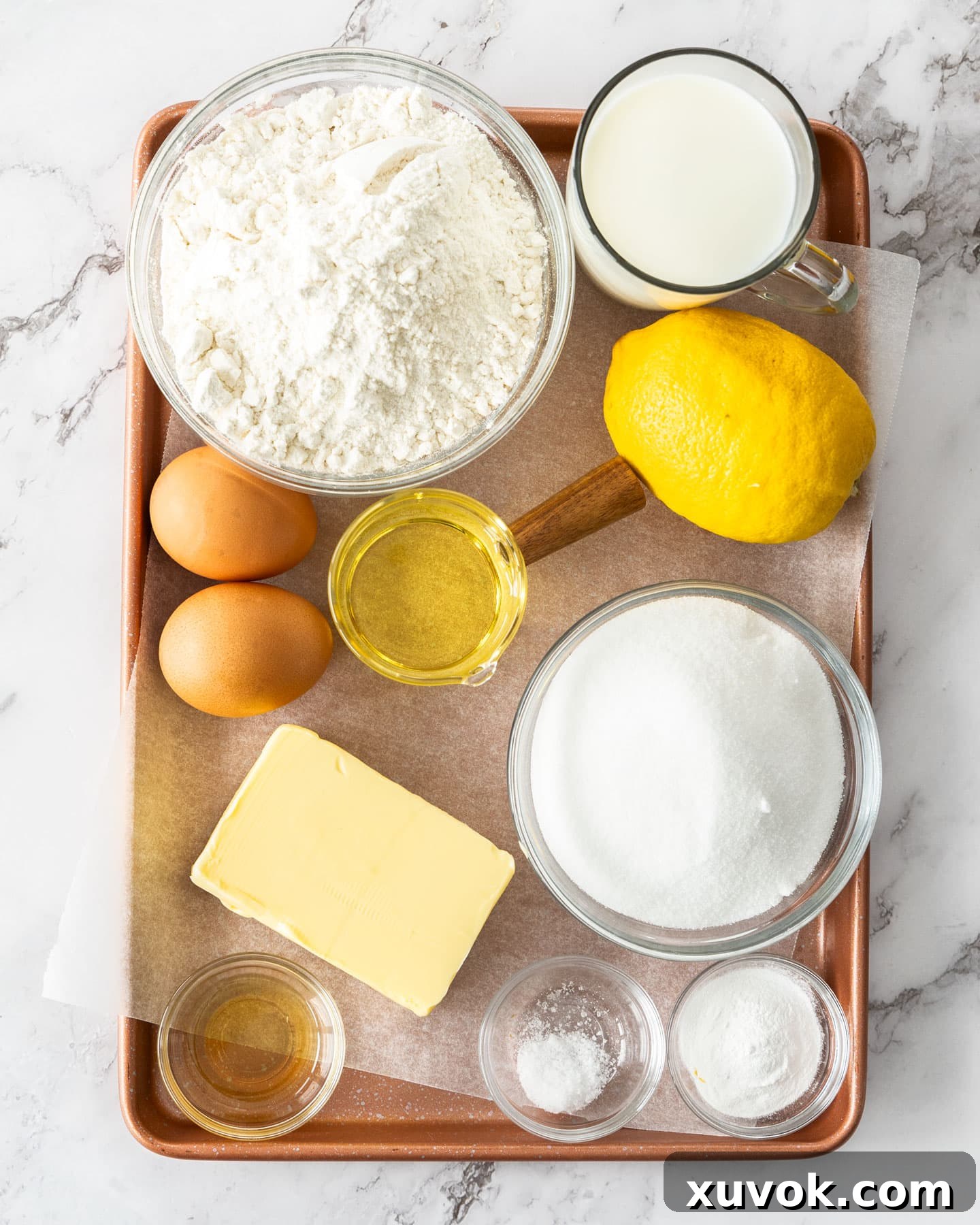 A flat lay photograph showcasing all the fresh ingredients needed to bake a delicious lemon drizzle cake, including lemons, eggs, flour, sugar, and butter.