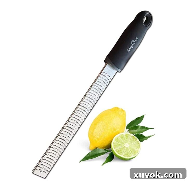 A close-up shot of a microplane zester grating zest from a fresh lemon, illustrating the best technique for fine zest.