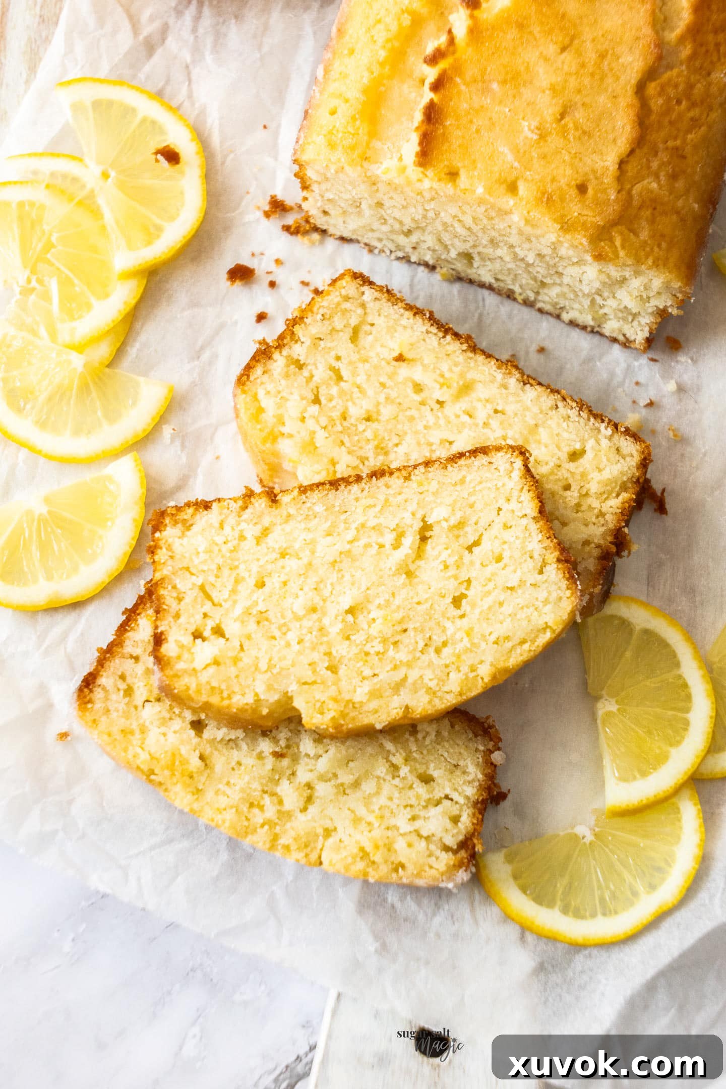 Three perfectly moist slices of lemon drizzle cake, stacked elegantly on a clean white surface, highlighting the soft crumb and glistening glaze.