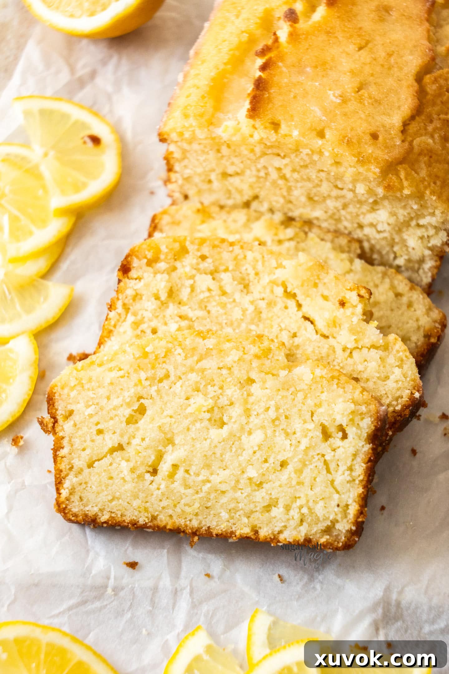 A tantalizing close-up of thinly sliced lemon drizzle cake, showing the moist crumb, the delicate crust, and the glistening glaze on top.