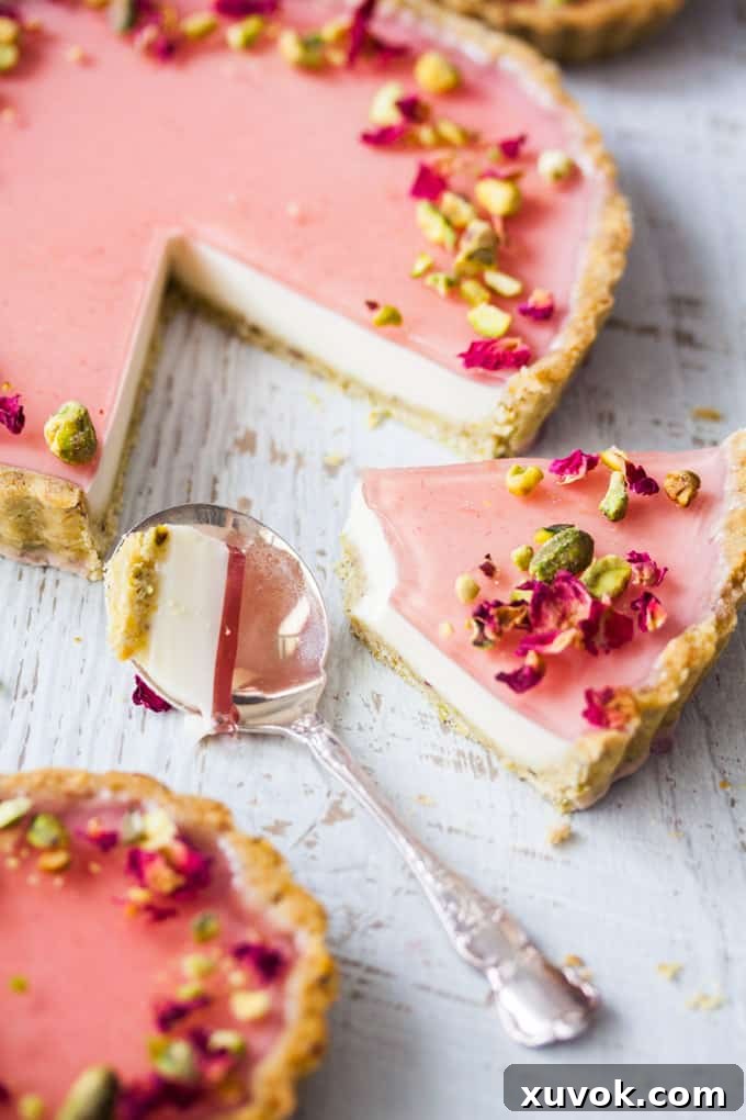 A stunning slice of Pistachio Rose Panna Cotta Tart, showcasing its perfectly layered components and elegant presentation.