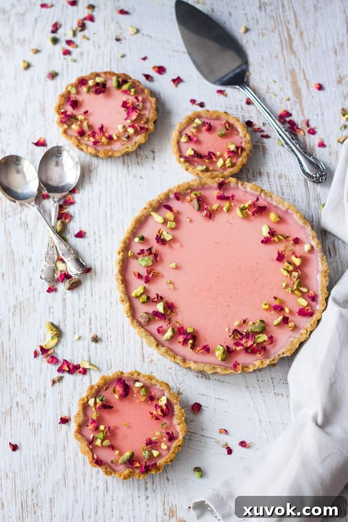 Pistachio Rose Panna Cotta Tart, featuring its distinct layers: a crunchy pistachio crust, smooth rose panna cotta, and a vibrant rose jelly.