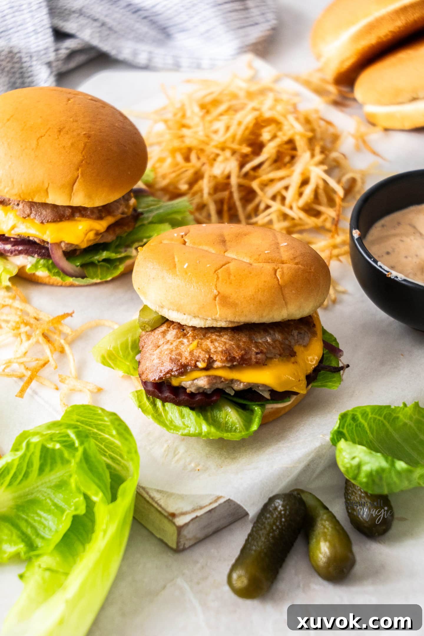 Two burgers on a platter with shoestring fries.