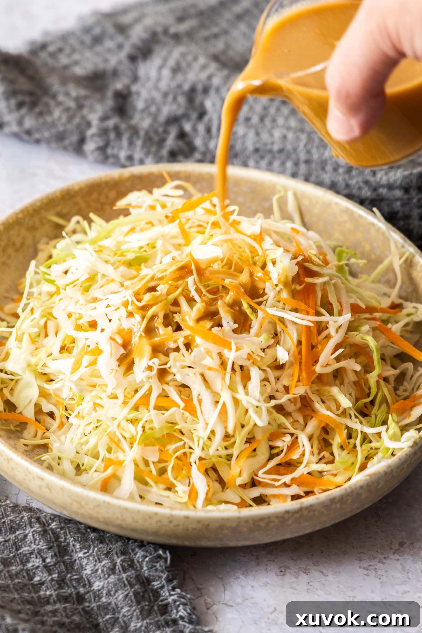 Japanese sesame dressing being poured over shredded cabbage.