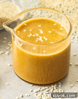 Closeup of a small glass jug filled with sesame dressing.