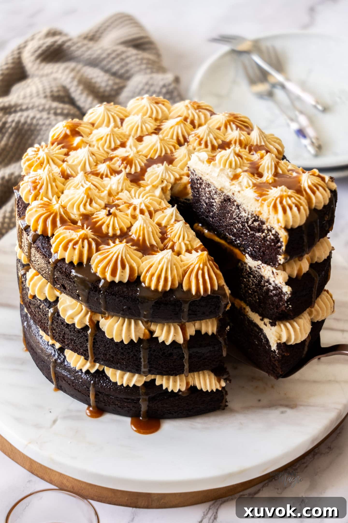 A hand gently removing a perfect slice from a magnificent chocolate salted caramel cake, revealing its rich layers and luscious filling.