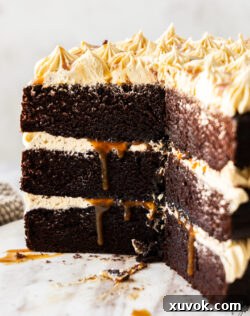 The cross-section of a beautifully layered chocolate salted caramel cake on a marble platter, highlighting its intricate design.