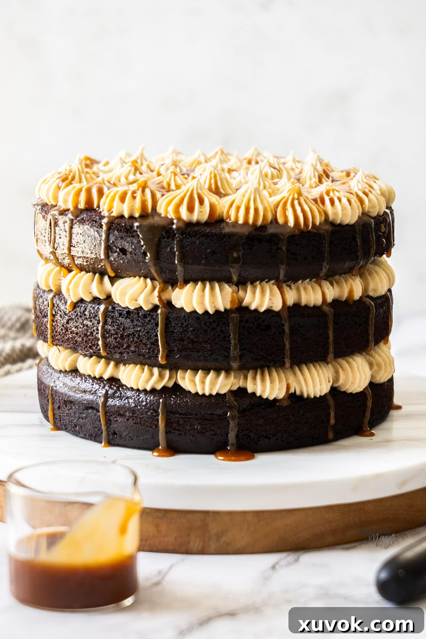 A perfectly stacked, triple-layer chocolate salted caramel cake, glistening with caramel drizzle, ready to be sliced and enjoyed.