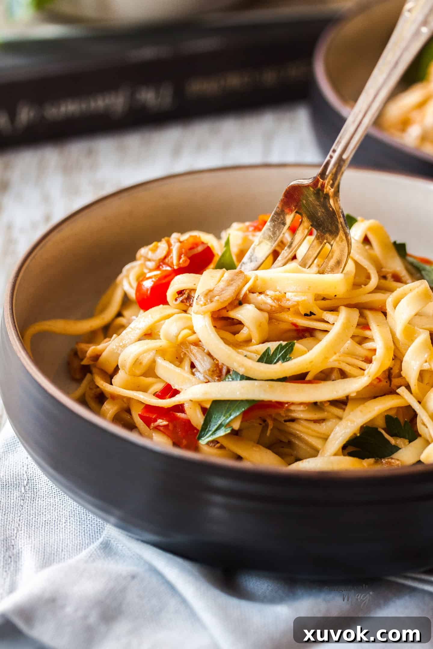 closeup: a fork digging into a bowl of linquine with crab and tomatoes in it