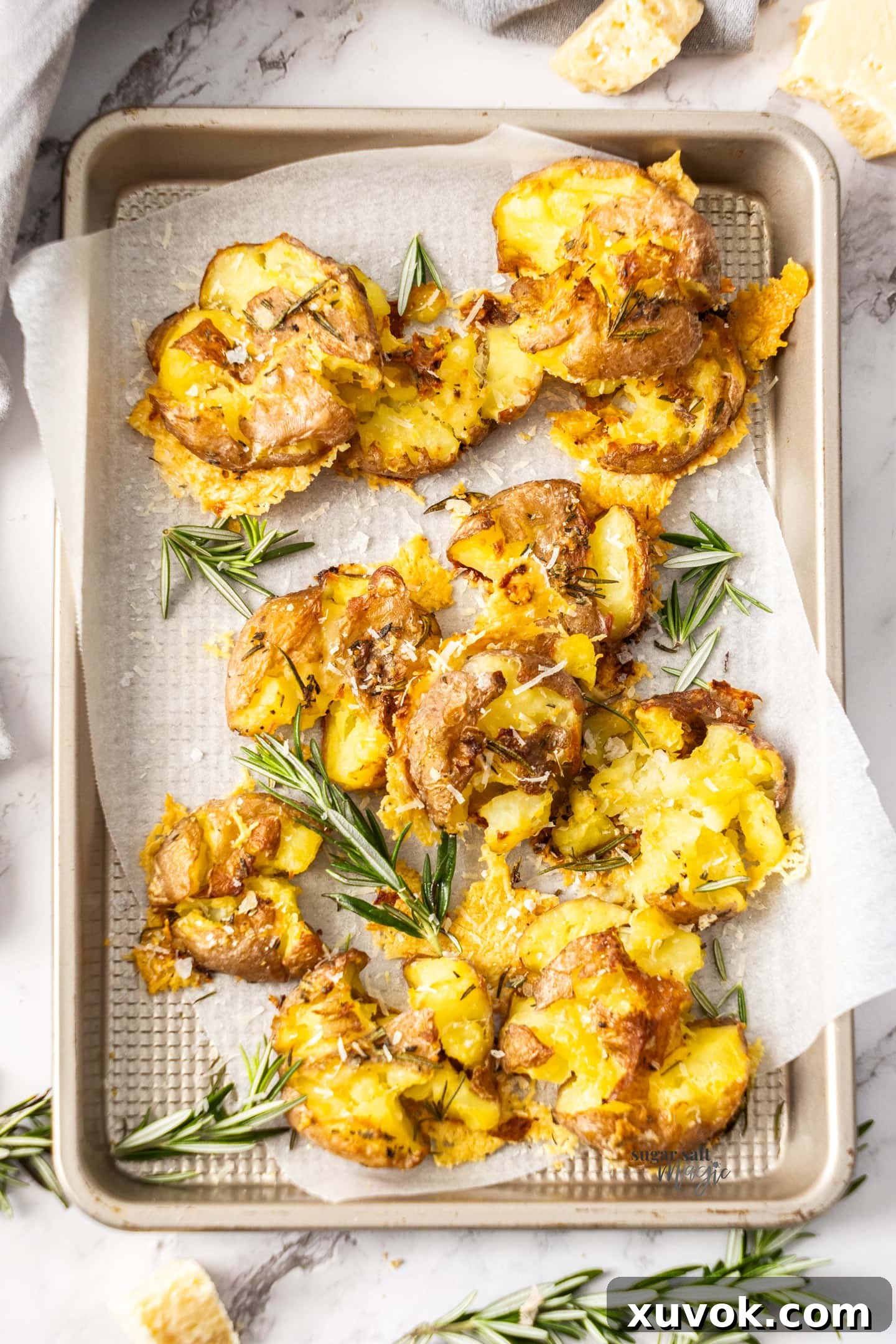 A baking tray loaded with parmesan smashed potatoes, golden brown and crispy.