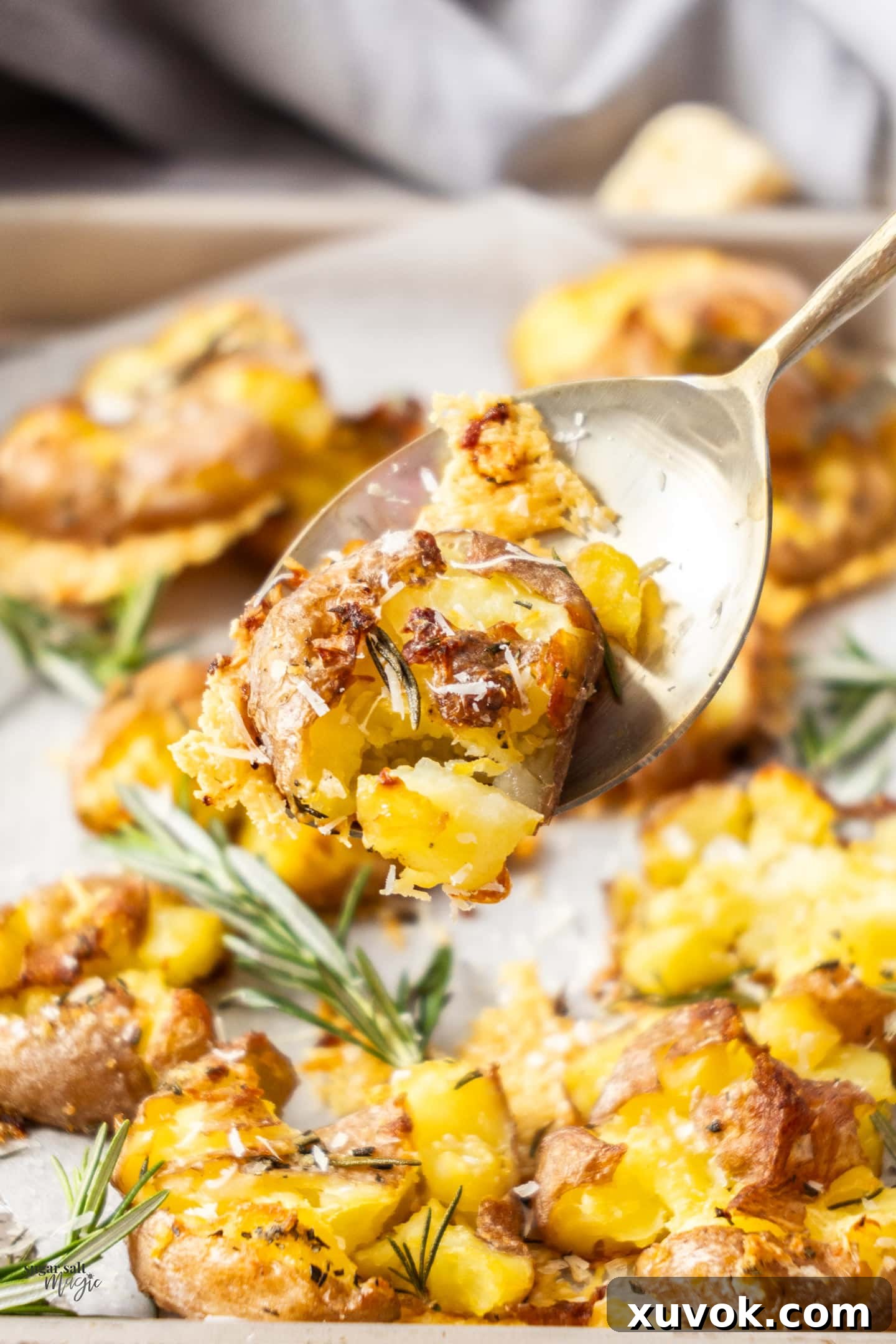 A serving spoon holding a perfectly golden and crispy smashed potato, showcasing its texture.