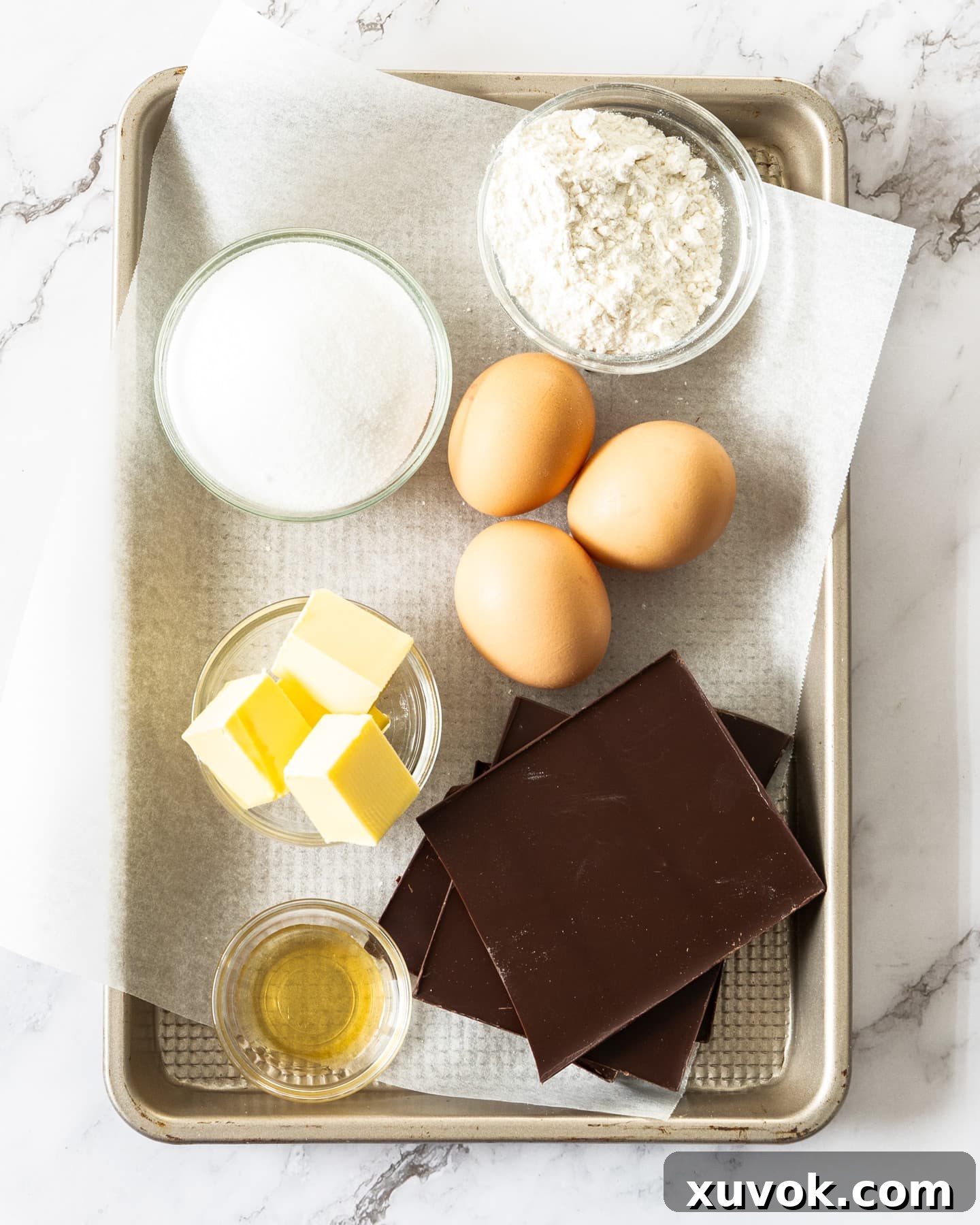 A collection of fresh ingredients for chocolate fondant, neatly arranged on a baking tray, ready for preparation.