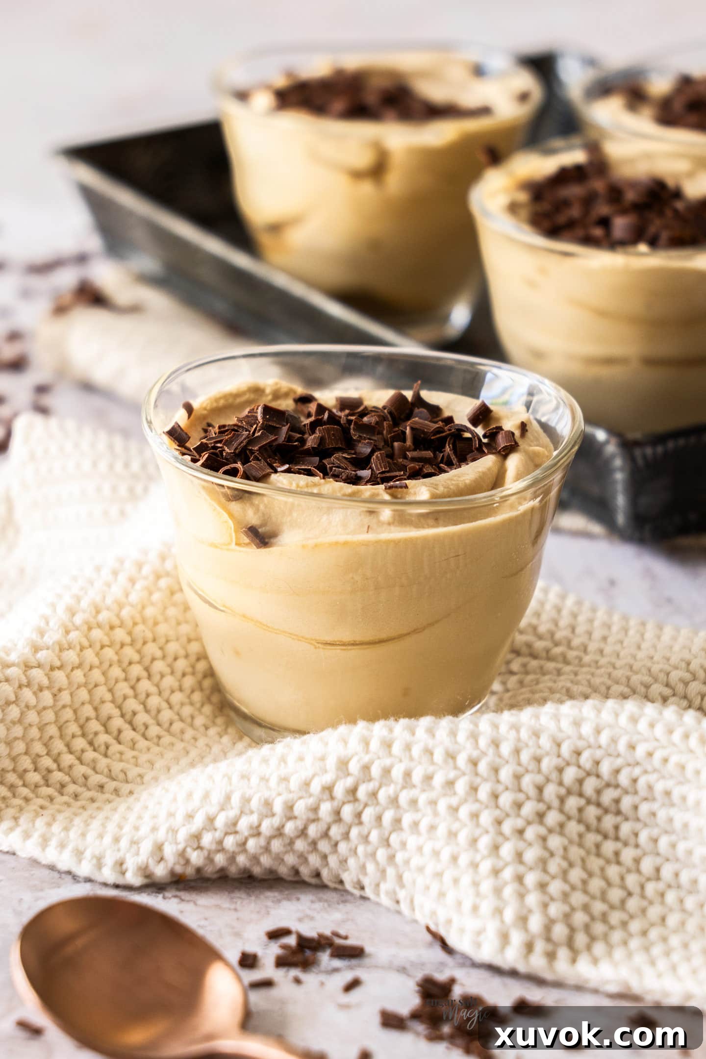 A single glass of creamy coffee mousse elegantly presented on a delicate crochet napkin, highlighting its smooth texture and inviting appeal.