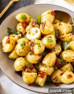Closeup of a bowl full of cooked potatoes with pieces of prosciutto and parsley