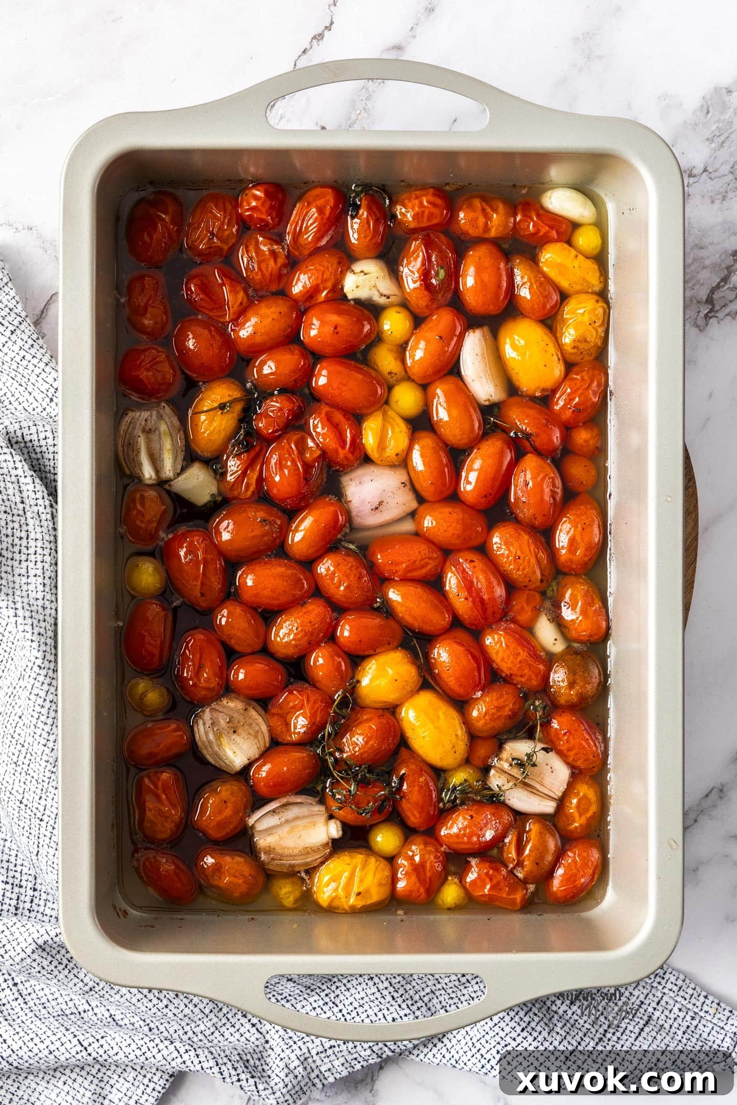 Overhead shot of freshly baked cherry tomato confit, glistening with infused oil and herbs.