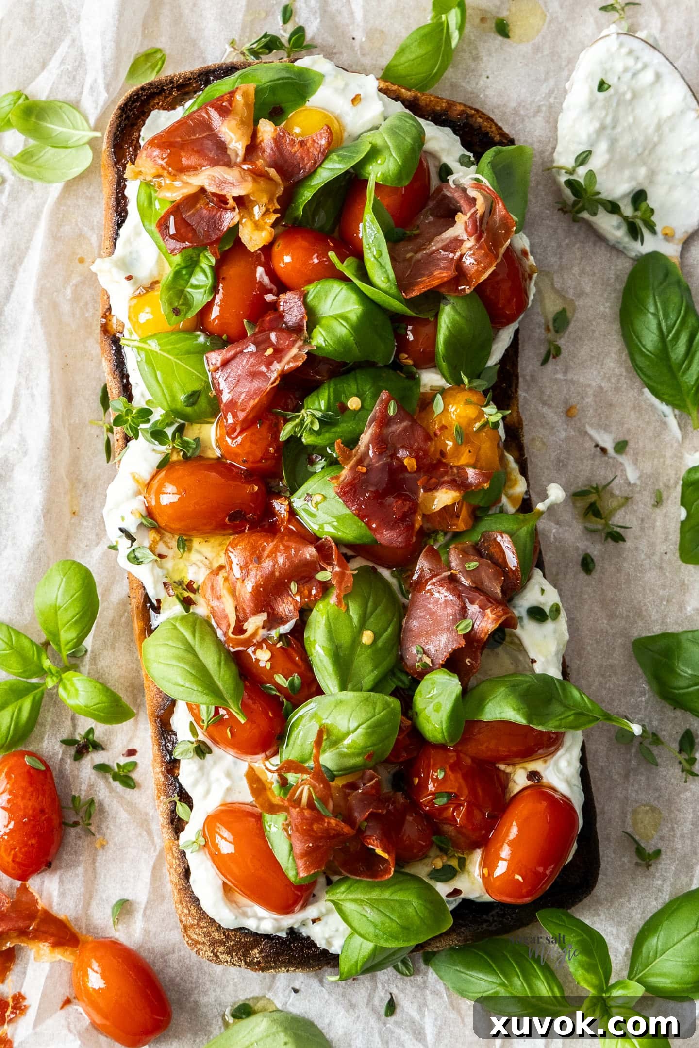Top-down view of slow-roasted tomato bruschetta with creamy ricotta, basil, and crunchy prosciutto, featuring tomato confit.