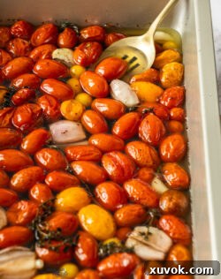 A spoon in a pan full of confit tomatoes.