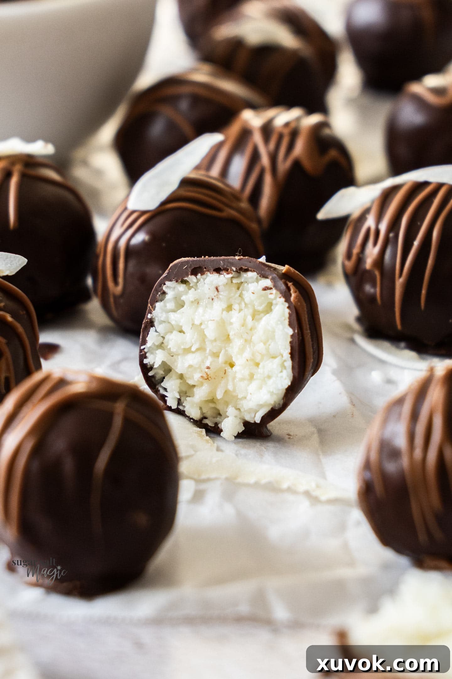 Extreme closeup of a chocolate covered coconut ball cut in half, revealing the moist coconut interior.