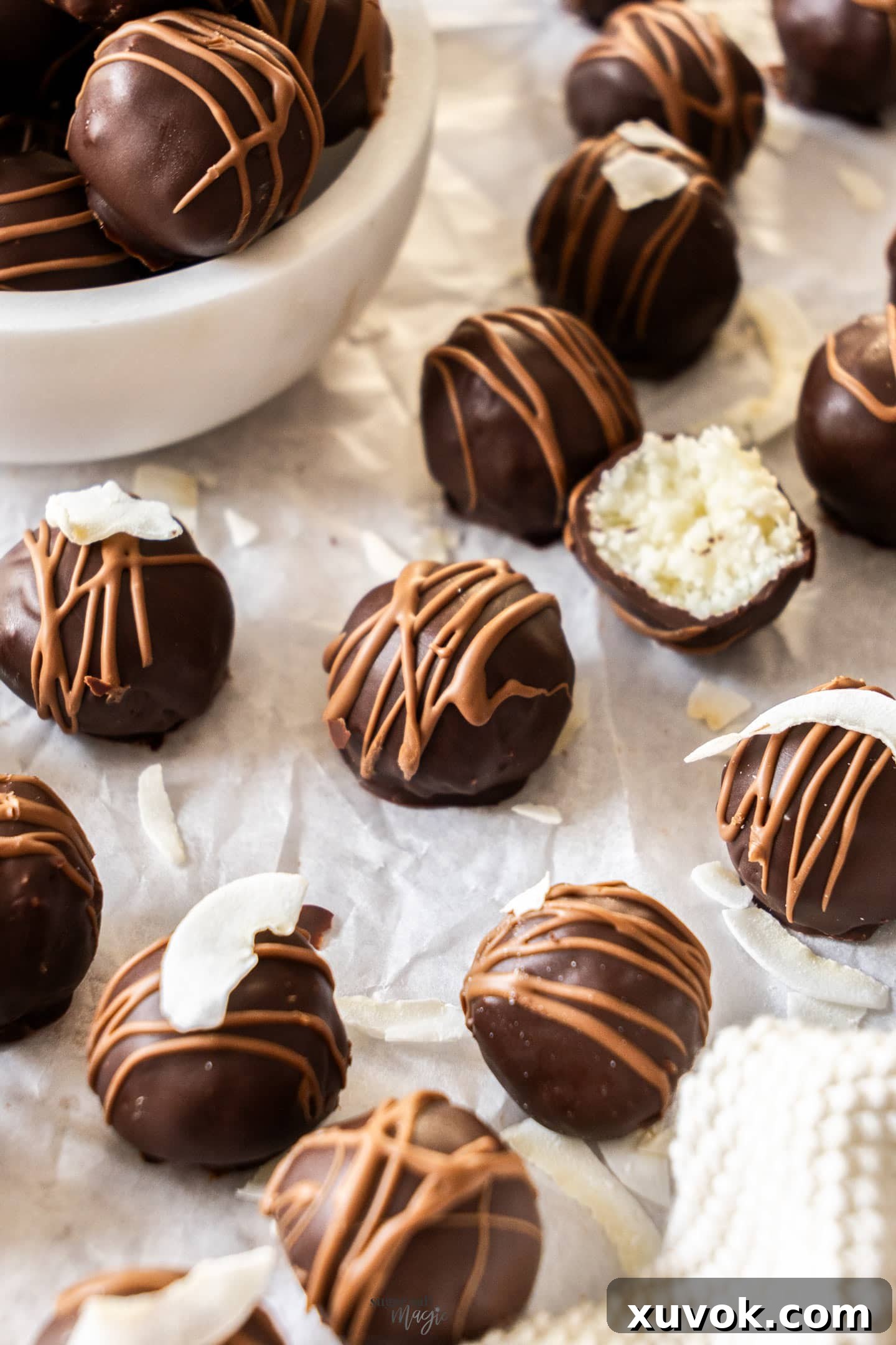 A close-up shot of a batch of chocolate covered coconut balls, showcasing their perfectly round shape and glossy chocolate coating.